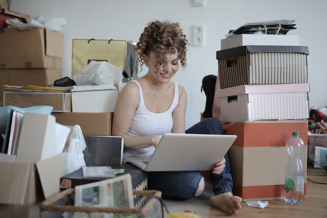 Woman researching how storage can simplify your NYC move while sitting on the floor among packed boxes